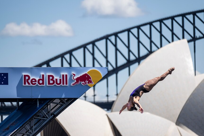 Meili Carpenter dives in front of the Opera House and Harbor Bridge