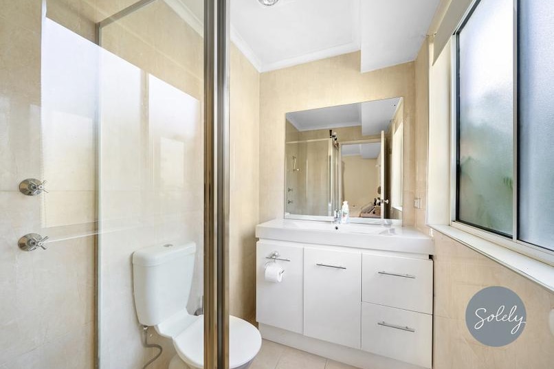 A smallish bathroom with shower, toilet and sink.