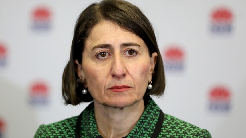 An unsmiling Gladys Berejiklian wears a green knitted blazer during a media conference.