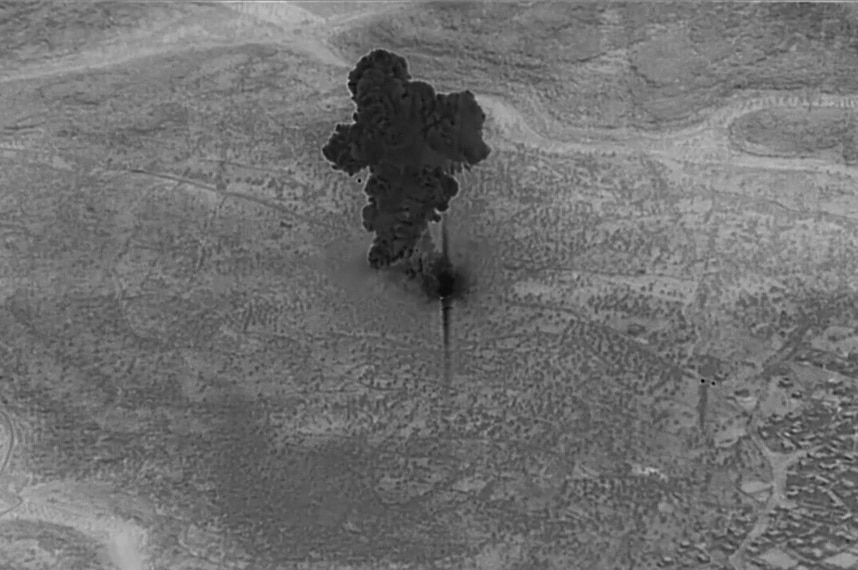 A still black-and-white image from a video shows smoke rising from the compound of IS leader Abu Bakr al-Baghdadi in Syria.