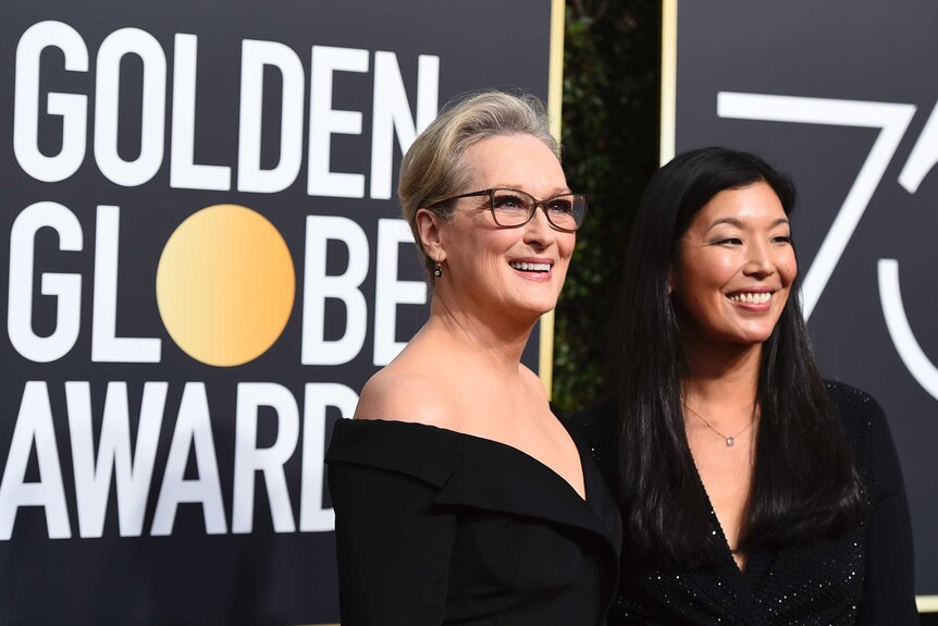 Meryl Streep, left, and Ai-jen Poo smile in front of Golden Globes sign