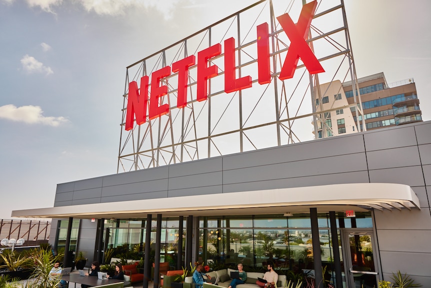An exterior shot of a Netflix office, which has a large Netflix logo on scaffolding on its roof