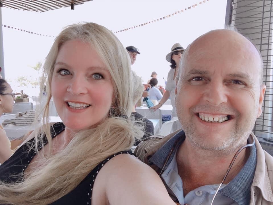 A man and woman take a selfie in a restaurant. They are both smiling at the camera.