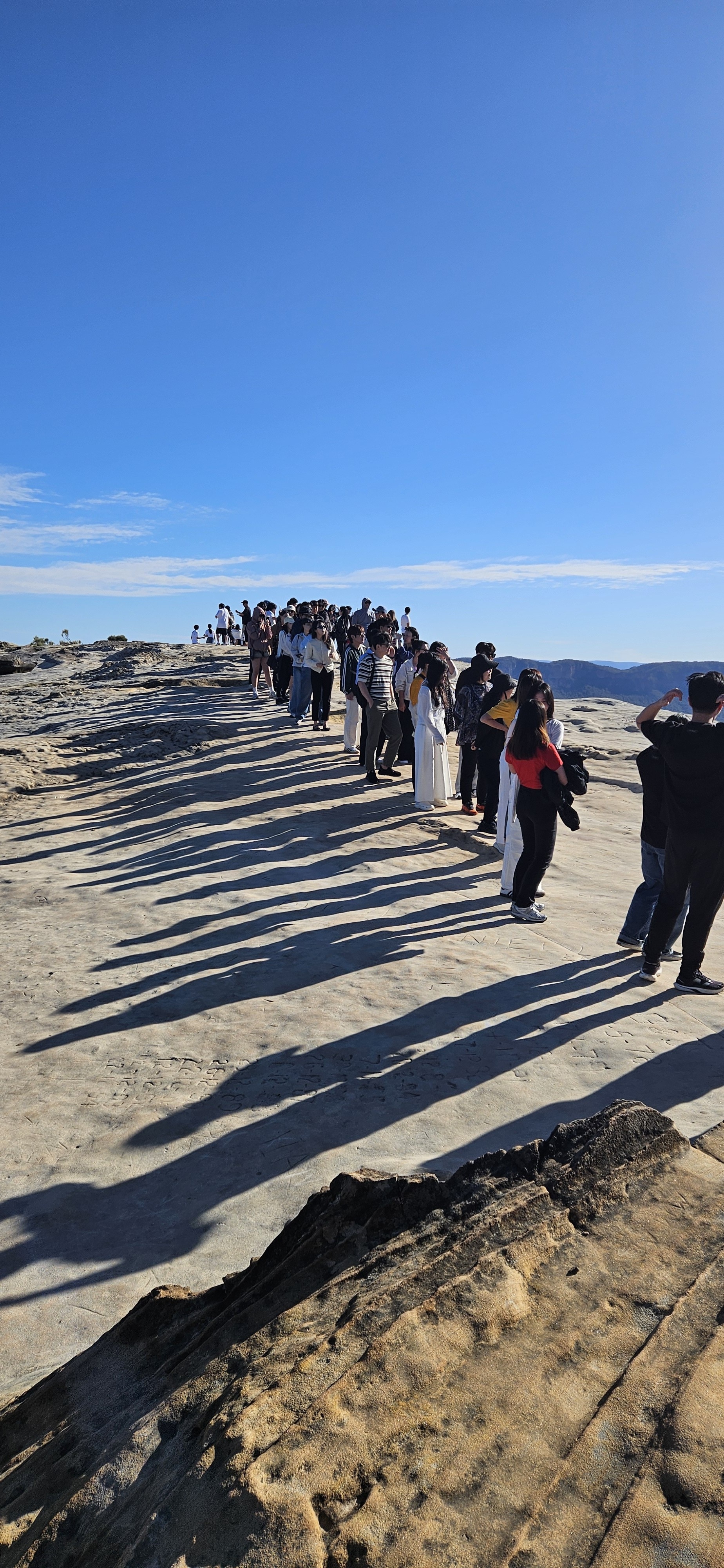 Line of people on a white sandstone rock.