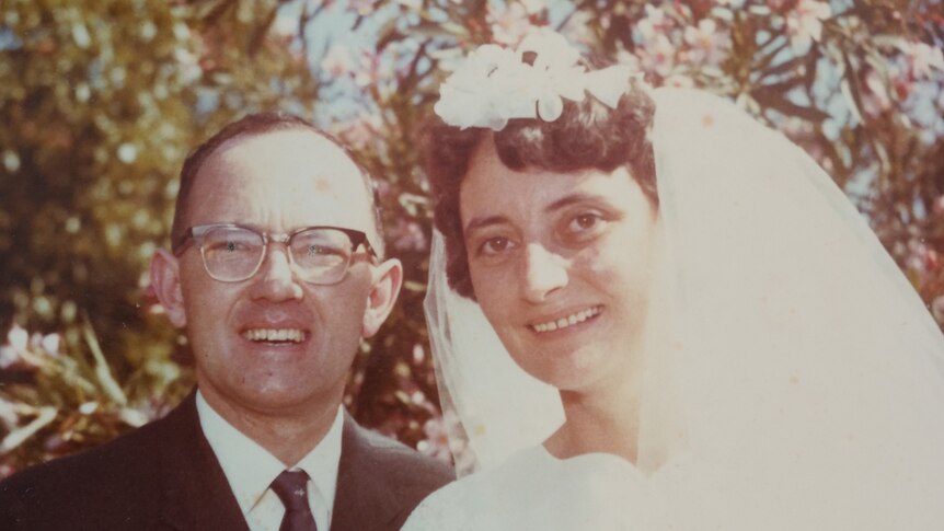 In a historic photo, Stan smiles while standing next to his wife in a wedding dress