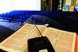 a wireless microphone sits on a Bible in an empty church