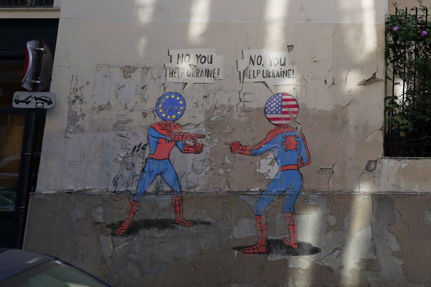 An image of 'fake graffiti' in Paris - two spidermen, one Europe, the other US fighting over who to help Ukraine.