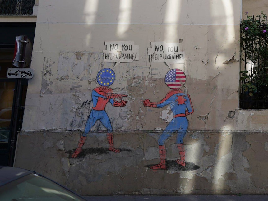 An image of 'fake graffiti' in Paris - two spidermen, one Europe, the other US fighting over who to help Ukraine.