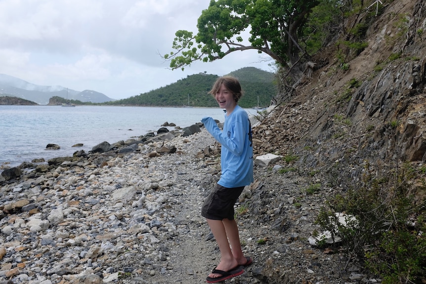 Alexander Neville smiling on a beach.