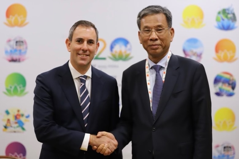 Jim Chalmers and Liu Kun standing side by side, shaking hands for the camera.