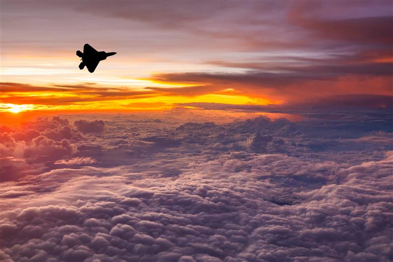 Fighter jet in the clouds at sunset