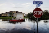 Residents paddle though their flooded neighbourhood streets on a little boat.