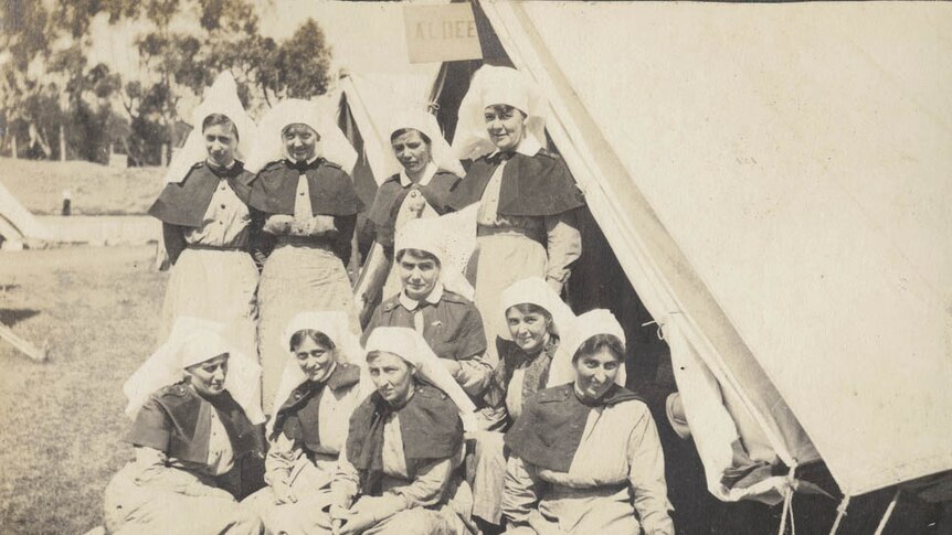 An old photo from 1919 of a group of nurses dressed in uniform standing outside a tent