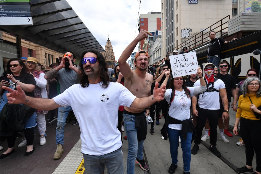 Protesters without masks, one holding an anti-vaccine sign.