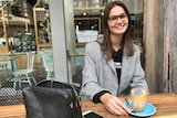 Erin McIver sits at a coffee table.