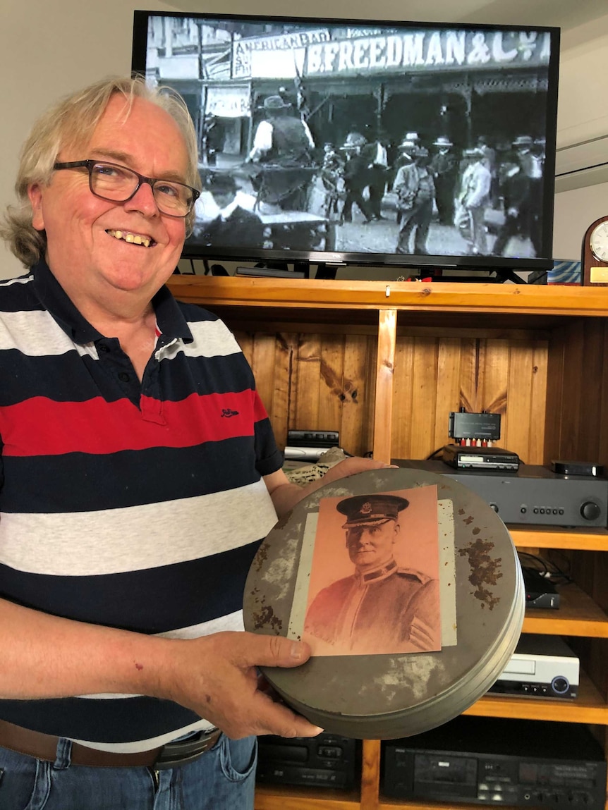 A man holds up a black and white photo of his grandfather.