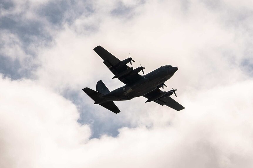 A Canadian Air Force Hercules patrol plane flying in a cloudy sky