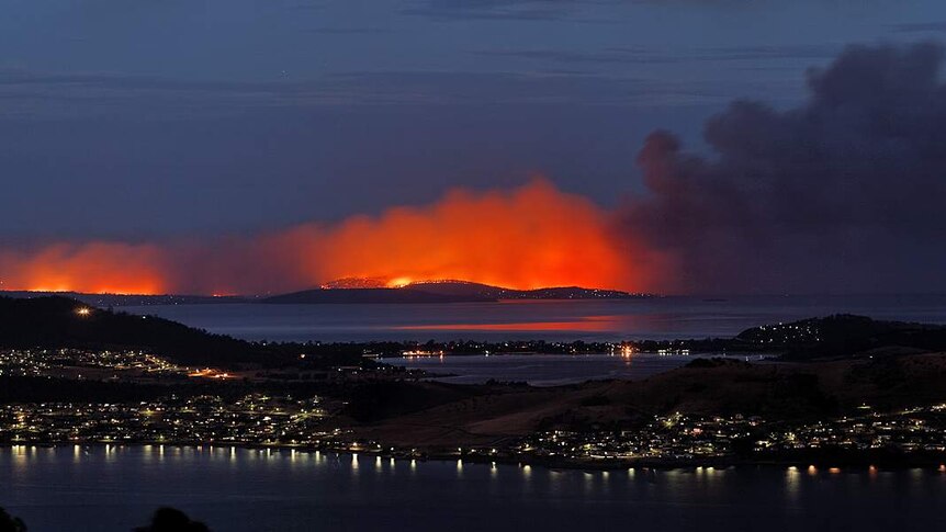 Flames glow through the smoke of the bushfires on the Tasman Peninsula near Hobart, January 4, 2013.