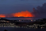 Flames glow through the smoke of bushfires on the Tasman Peninsula in 2013.