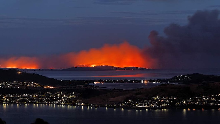 Flames glow through the smoke of the bushfires on the Tasman Peninsula.