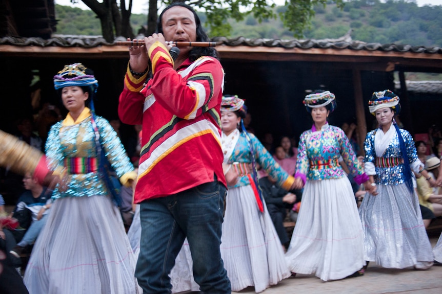 Mosuo villagers perform a fire dance for tourists