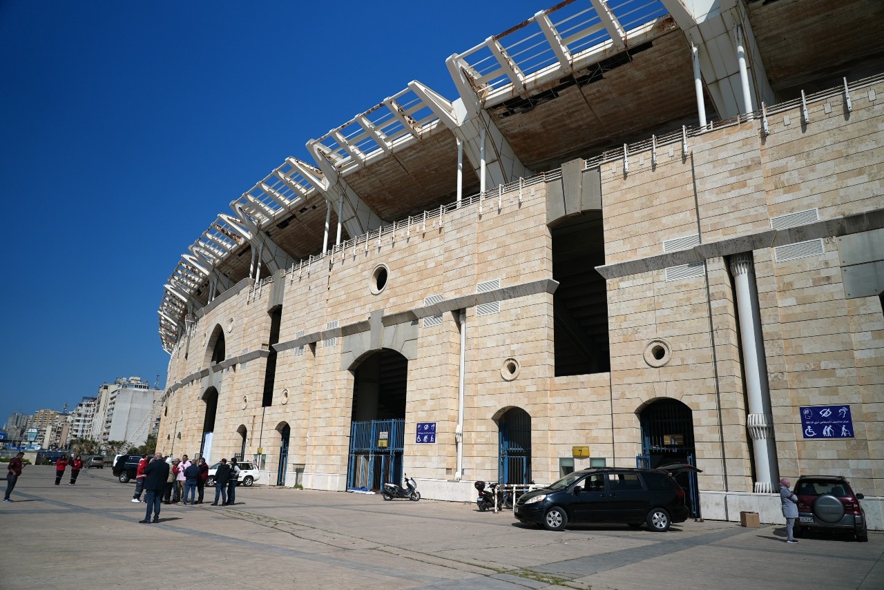 The exterior of a large building, with several people standing nearby.