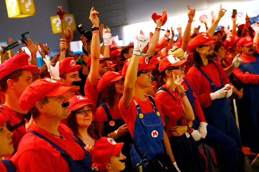 A crowd of people dressed in red and blue as Mario. 