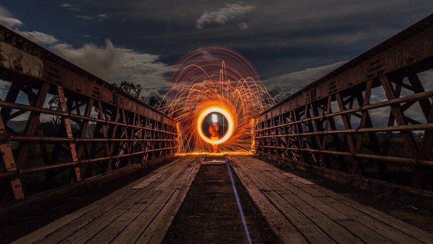 Time lapse of a fire baton being spun at night, the baton forming a circle of flame.