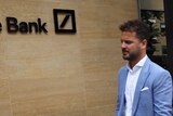 Two men in suits carrying bags in front of the Deutsche Bank in London.