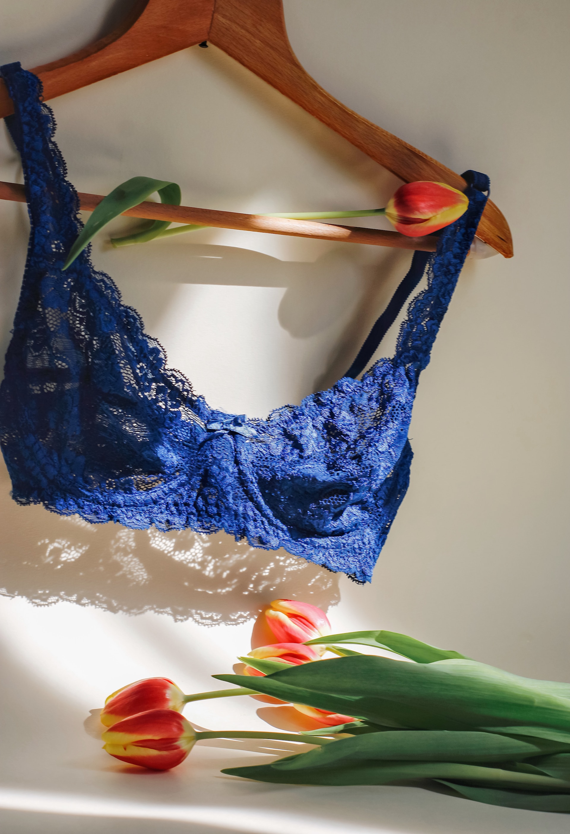 A navy blue lacy bra hangs on a wooden coathanger.