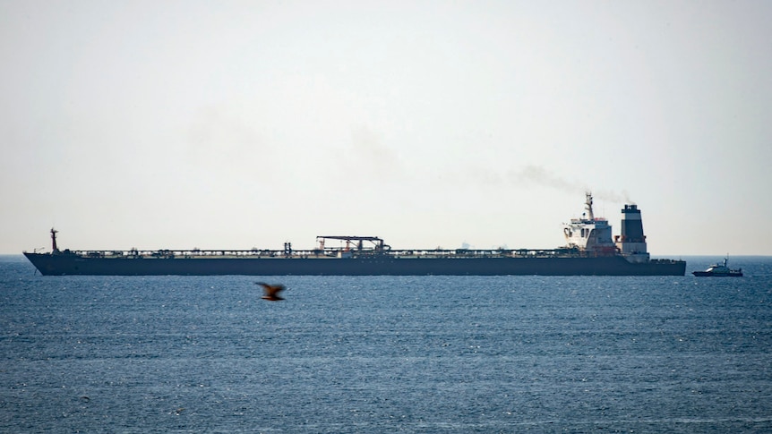 A long super tanker is seen anchored near a Royal Marine patrol vessel.