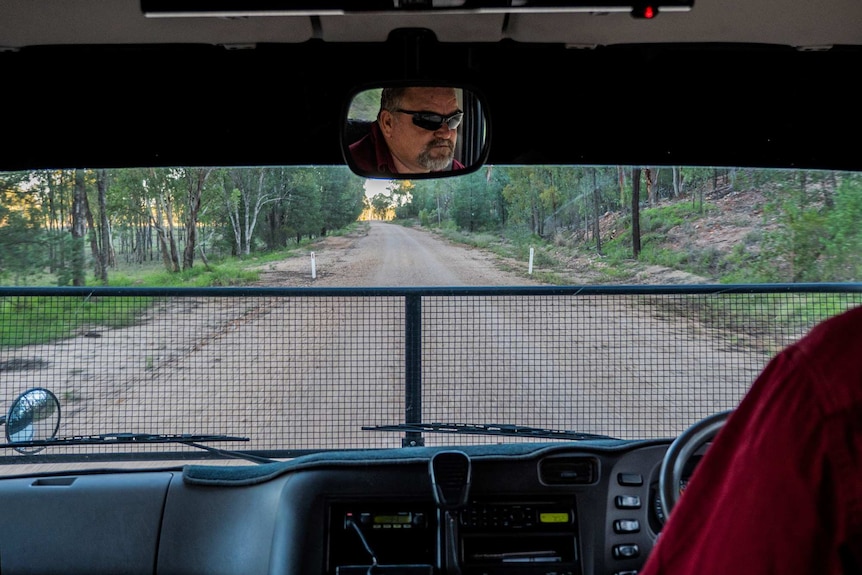 A reflection of the bus driver along a dirt road