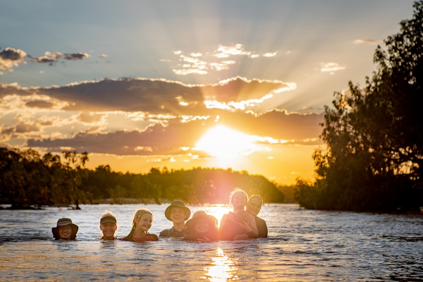 A family in a river with a hot sun behind them