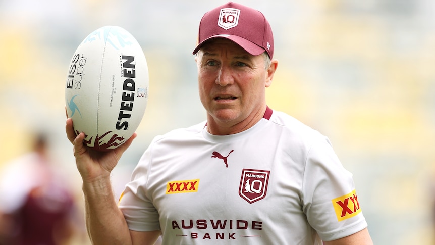 Wearing his Maroons training attire, Paul Green holds a football up near his head