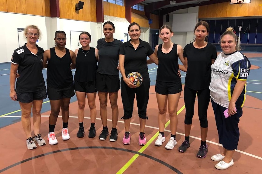 Group of Indigenous netballers and coaches smiling for a photo 