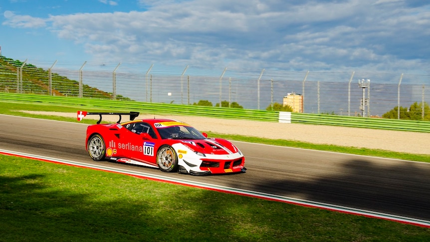 Red Ferrari race car on a race track.