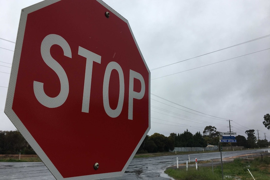 a stop sign at a rural intersection near mildura with powerlines in the background against a cloudy sky