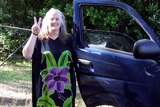 Heather Gladman making peace sign beside car