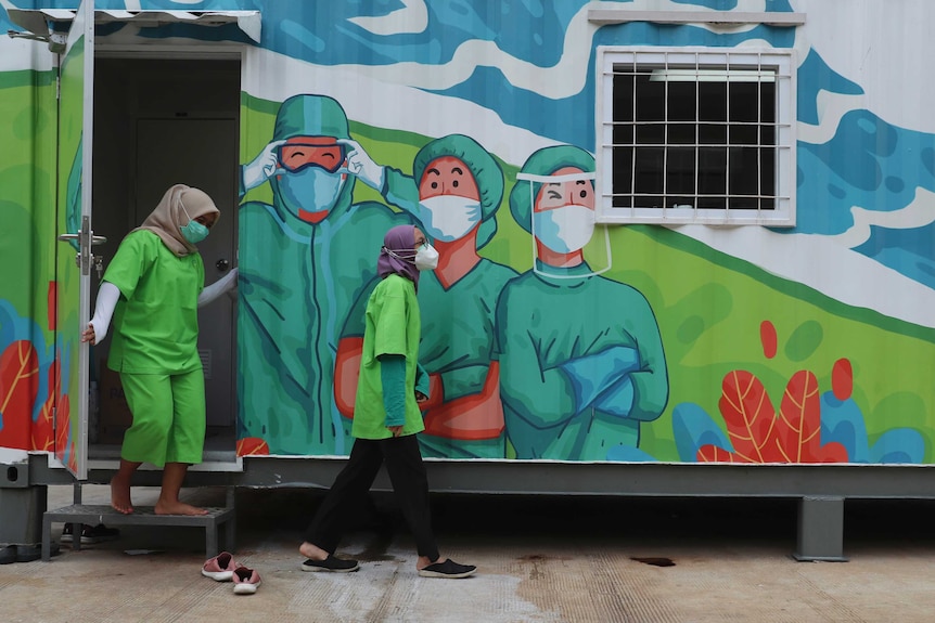 Health workers walk out of a mobile laboratory before analysing coronavirus samples in Jakarta.