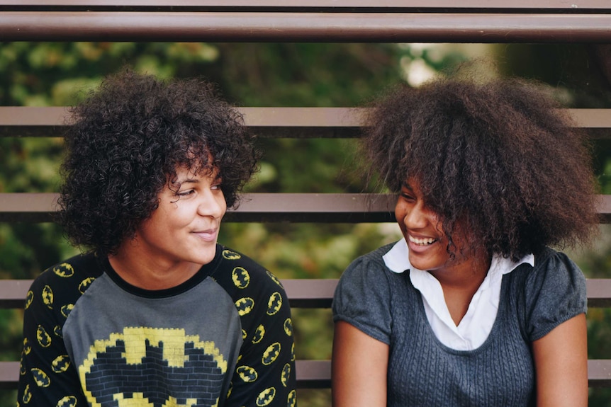 Two young people, might be siblings, laughing and smiling together