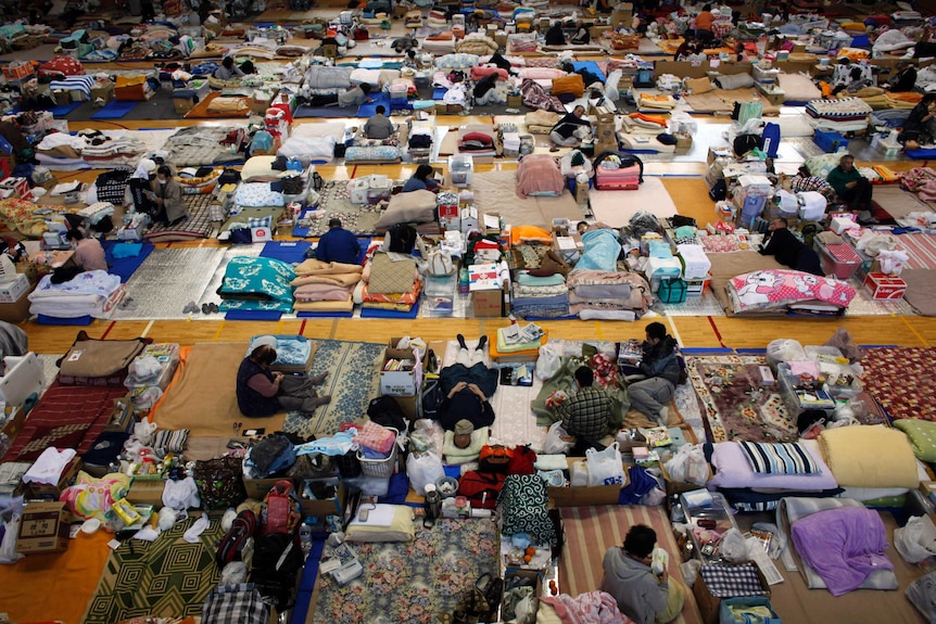 A gymnasium turned into an evacuation centre filled with people and their belongings
