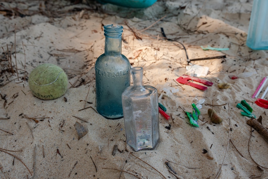 trash and glass bottles on sand