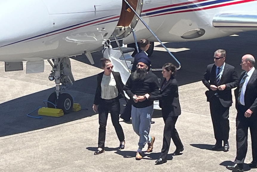 Lead investigators escort Mr Singh from the plane.