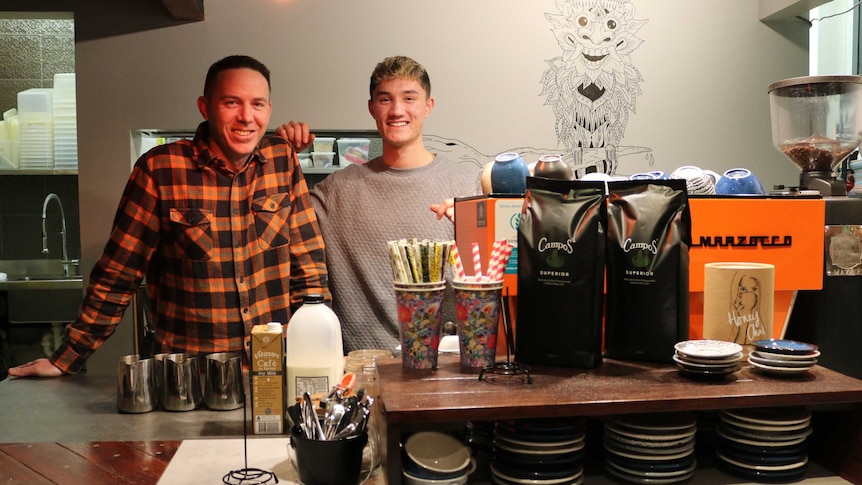 Gavin and Zac smile, standing behind the counter at Kita cafe.