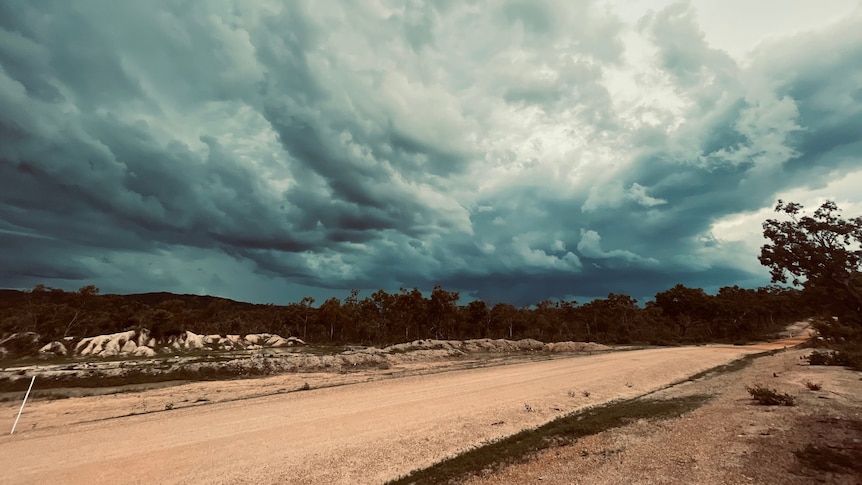 storm clouds form over a dirt road