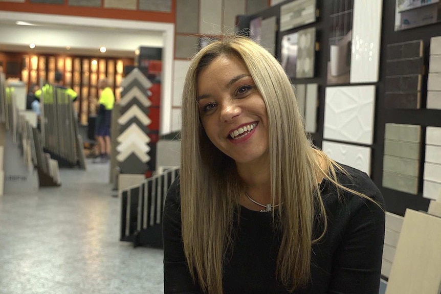 Medium profile shot of a woman smiling inside a shop.