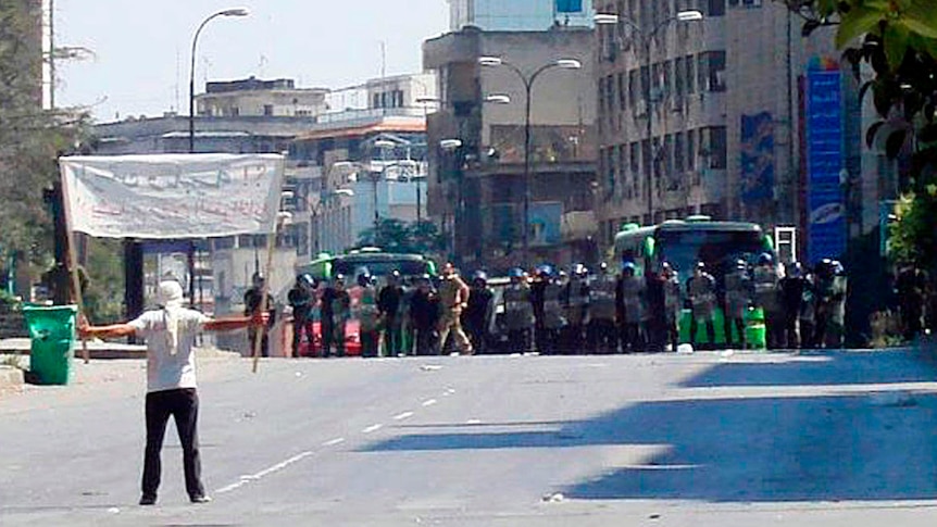 Unrest in Syria... a protester faces riot police at Khalidia