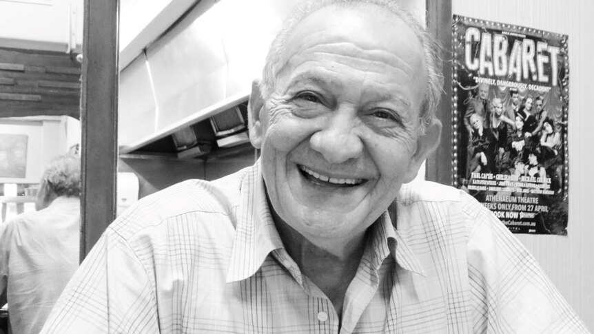 A black and white portrait of a smiling man in his 70s