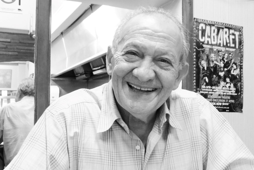 A black and white portrait of a smiling man in his 70s