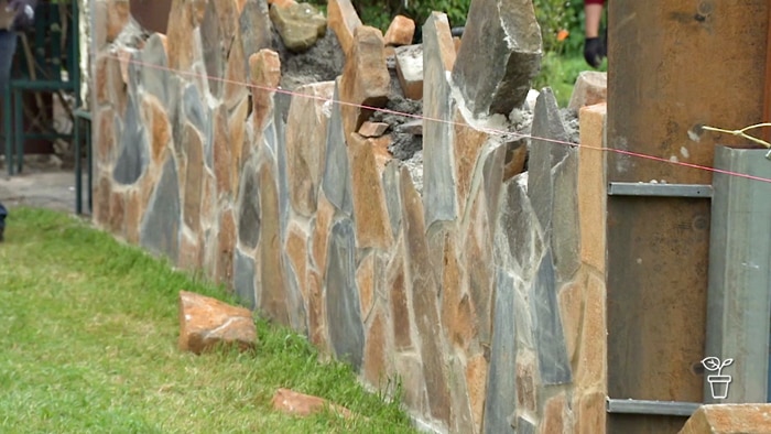 Sting lines on either side of handmade stone wall that is under construction